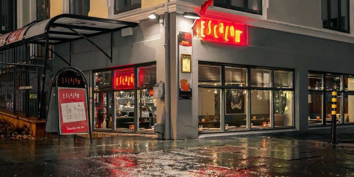 A building with a red neon sign reading "ESCALON" and a signboard with "Escalón" and "Tienda 2016-2018".