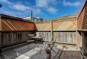 A patio with a wooden fence, a table, chairs, and a potted plant. - Sea House Dillon Beach - 2 Bed, 1 Bath - 5 Minute Walk To Beach (Dillon Beach)