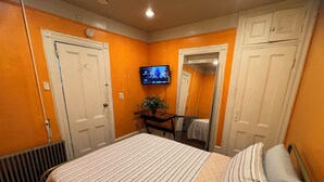 A bedroom with a bed, a TV, a radiator, and a mirror. - Newark's Art Deco 1-bdrm Oasis (Newark)