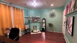 A living room with a fireplace, a large mirror, and a dining area with a table and chairs. - Newark's Art Deco 1-bdrm Oasis (Newark)