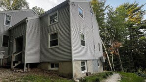 A two-story house with a sloped roof and multiple windows. - 1BR apartment next to the Pleasant Mountain with waterfront access (Bridgton)