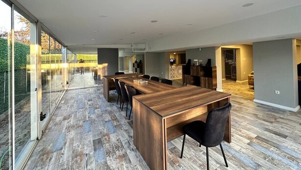 Una cocina moderna y espaciosa con una encimera de madera larga, paredes de vidrio y vistas al exterior.
