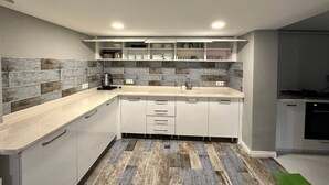 Una cocina moderna con armarios blancos, un salpicadero de baldosas grises y suelo de madera.