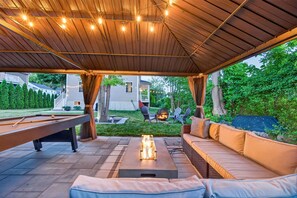 Um pátio externo com mesa de bilhar, lareira e área de estar.