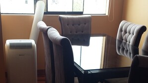 Una stanza con un tavolo da pranzo, quattro sedie, un termosifone e una finestra con persiane.