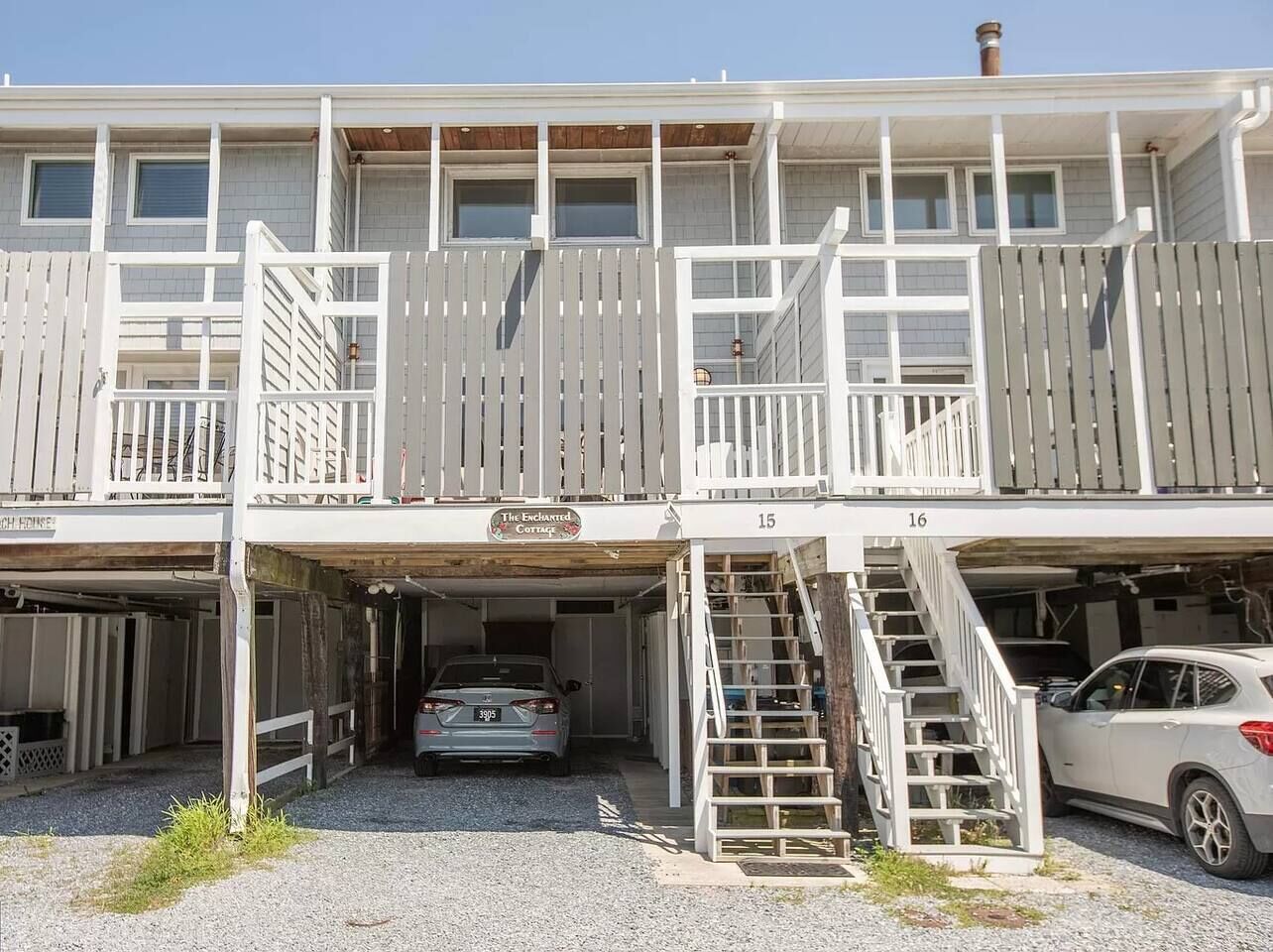 A two-story building with a covered parking area and a sign reading "The Enchanted Cottage."