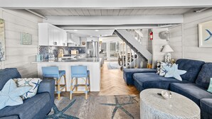 Een moderne woonkamer met een keuken, een trap en een eethoek.