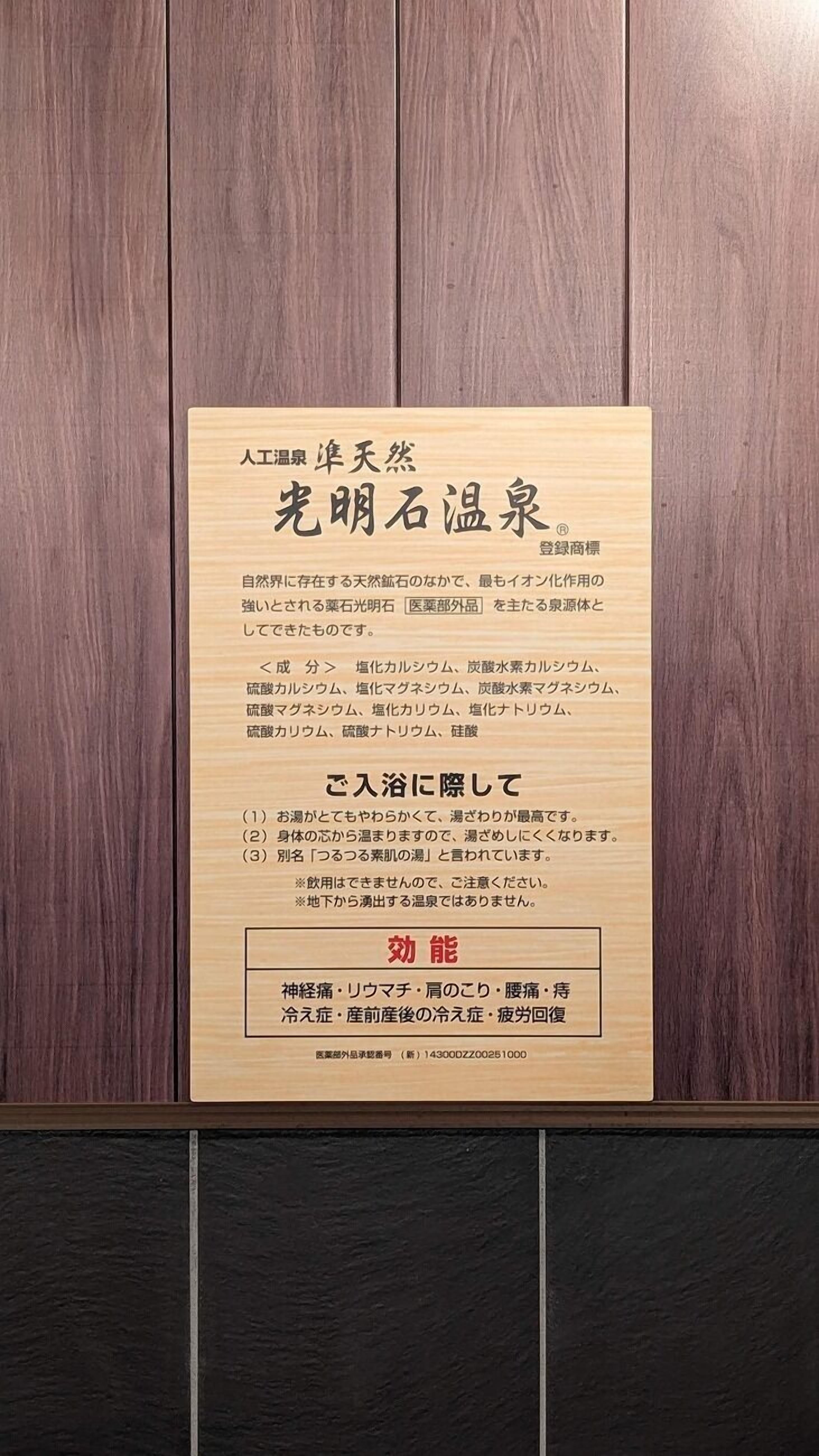 Una placa de madera con texto en japonés, probablemente ofreciendo información sobre un hotel o establecimiento.