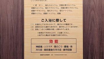 Una placa de madera con texto en japonés, probablemente ofreciendo información sobre un hotel o establecimiento.