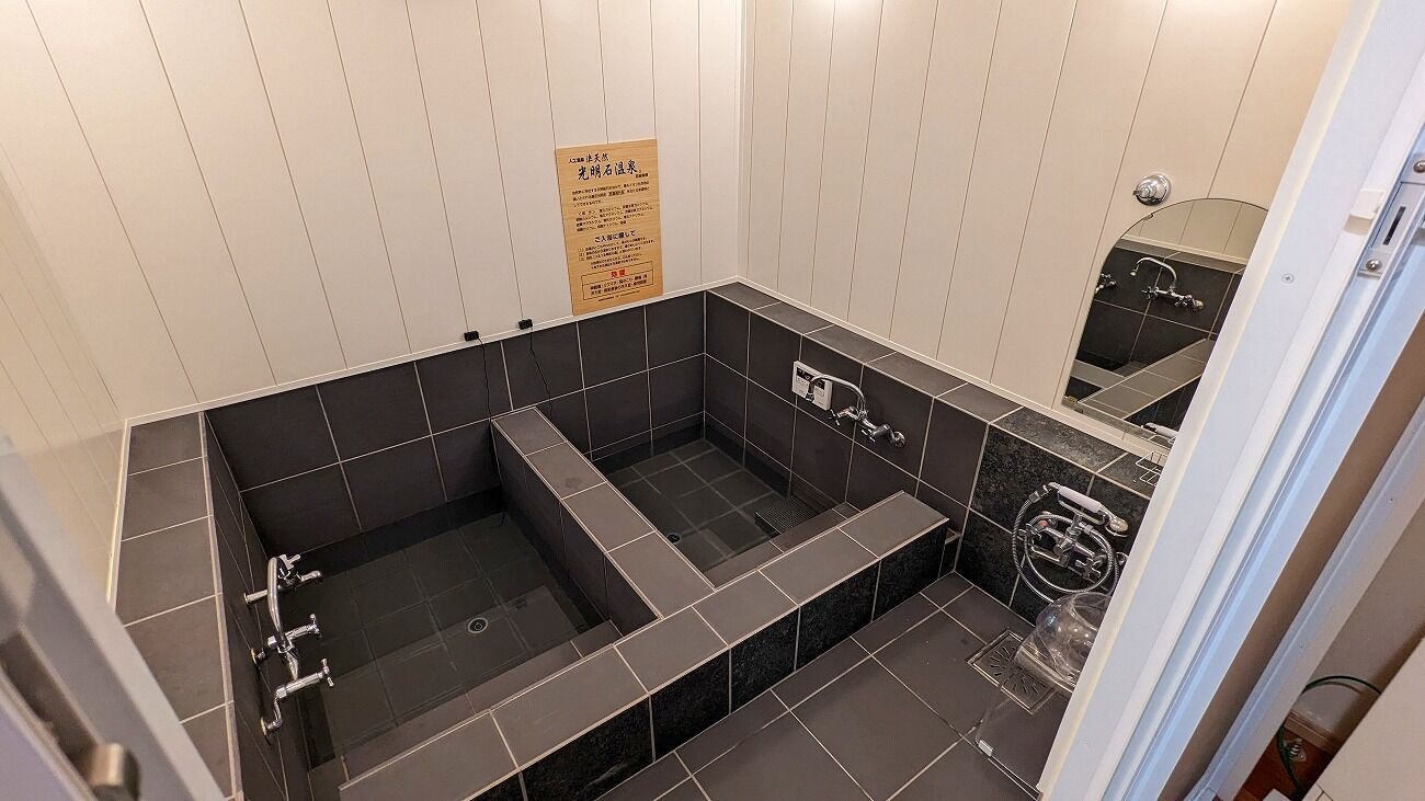 A modern bathroom with a large bathtub, a shower area, and a mirror.