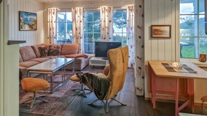 Een gezellige woonkamer met een bank, fauteuil, salontafel en televisie.