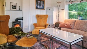 Een gezellige woonkamer met een open haard, een kinderstoel, een bank en een tafel.