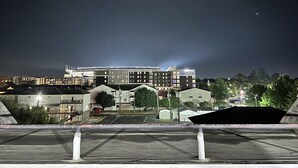 Ein mehrstöckiges Hotel mit modernem Design, das mit einer markanten Dachterrasse und einem Parkplatz im Vordergrund besticht.