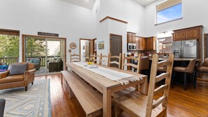 Àmplia zona d'estar amb taula de dinar de fusta, seients i una zona relaxant amb sofà.