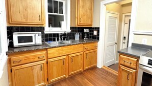 A kitchen with wooden cabinets, a microwave, a stove, and a window. - 2B1BA  Central - Airport, Riverside, Zoo, Beach (Jacksonville)