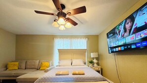 A bedroom with a bed, a ceiling fan, a TV mounted on the wall, and a window with curtains. - 2B1BA  Central - Airport, Riverside, Zoo, Beach (Jacksonville)
