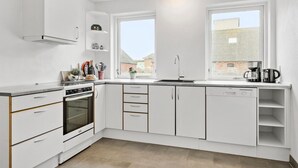 A modern kitchen with white cabinetry, a built-in oven, a dishwasher, and a window providing a view of the outside. - 4 bedroom nice home in Harboøre (Harboøre)