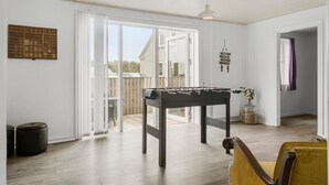 A spacious room with a foosball table, large windows, and a view of the outside. - 4 bedroom nice home in Harboøre (Harboøre)