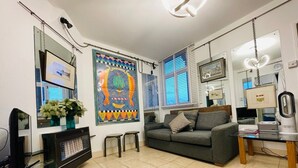 Ein Wohnzimmer mit einer Couch, einem Couchtisch, einem Fernseher und einer Wand mit einem farbenfrohen Wandbild.