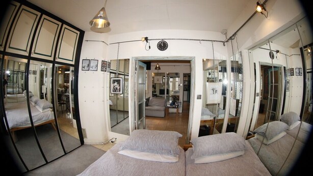Ein Zimmer mit zwei Betten, einem großen Spiegel und einer Wanduhr.
