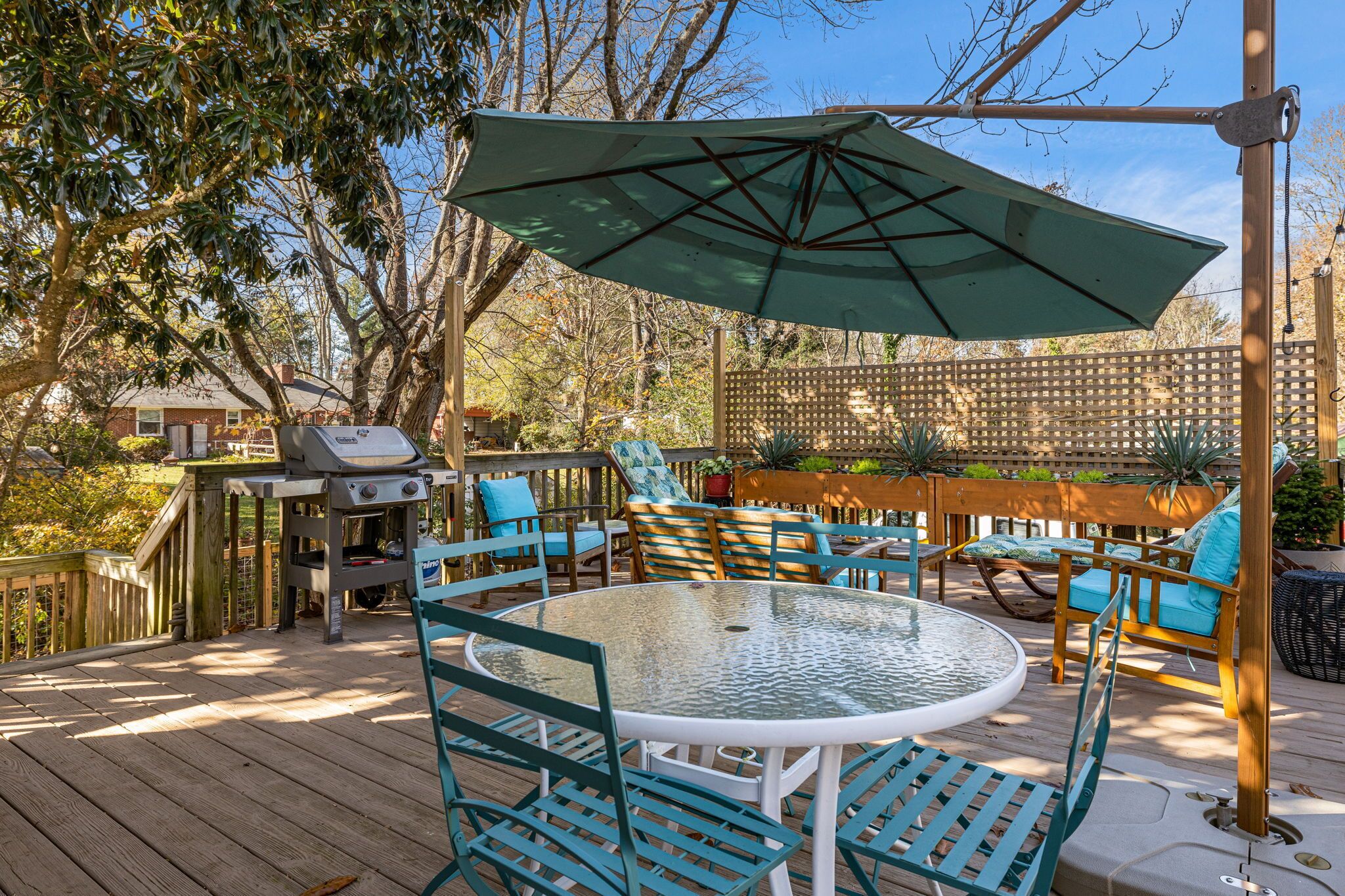 Une terrasse avec un barbecue, du mobilier d’extérieur et un grand parasol.