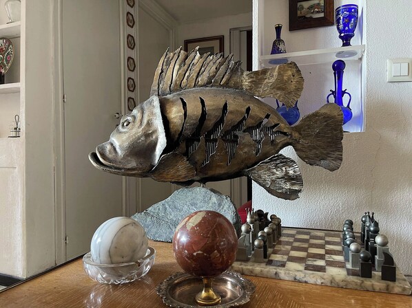 A fish sculpture on a table with a chessboard and decorative items. - di Alfredo (Roma)