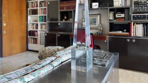 A room with a clear glass sculpture on a metallic table, surrounded by bookshelves filled with books and decorative items. - di Alfredo (Roma)
