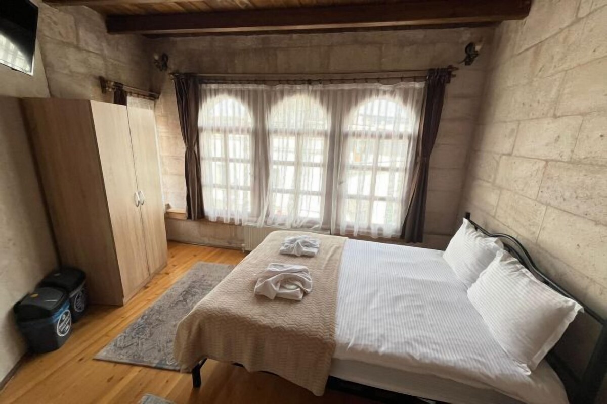 A bedroom with a bed, a wardrobe, a window with curtains, and a radiator.