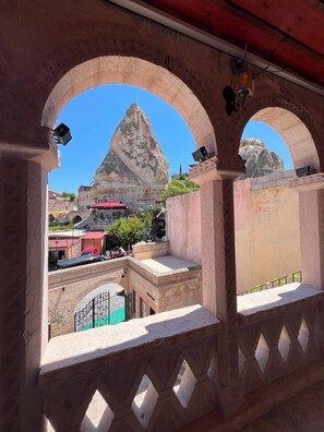 A stone balcony with arched railings overlooking a rocky mountain and a town below. - Mustafa Bey Konağı (Nevsehir)