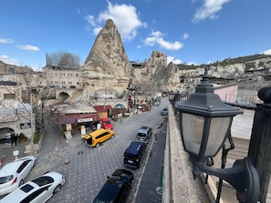 A street view with a prominent rock formation, a cave hotel, and a restaurant. - Mustafa Bey Konağı (Nevsehir)