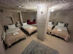 A room with three beds, a red chair, and a textured ceiling. - Mustafa Bey Konağı (Nevsehir)