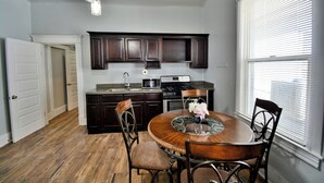 A kitchen with dark wooden cabinets, a round dining table with chairs, a microwave, and a stove. - Entire Home Near UTEP  (El Paso)