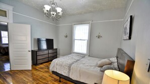 A bedroom with a bed, dresser, TV, and a chandelier. - Entire Home Near UTEP  (El Paso)
