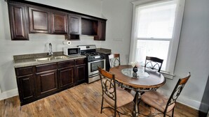 A kitchen with dark wooden cabinets, a granite countertop, a stove, and a dining table with four chairs. - Entire Home Near UTEP  (El Paso)
