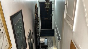 A narrow hallway with a patterned carpet, a black door at the end, and a radiator on the right.