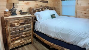 Una camera in una baita di legno con un letto, un comodino e una finestra con persiane.