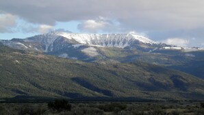 A mountain landscape with a snow-capped peak, dense forested hills, and a flat valley in the foreground. - Baxter Manor Spring City (Spring City)