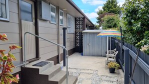 A residential building with a small patio area, a metal staircase, and a colorful umbrella.