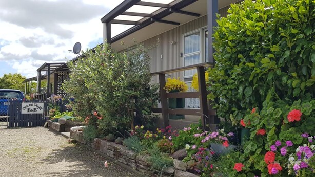 A building with a garden area, a wooden fence, and a sign that reads "One on Vogel B&B".