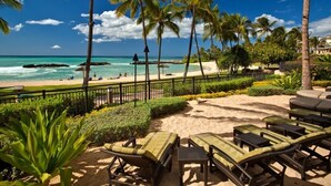 Un salon de plage avec des chaises longues, des palmiers et une vue sur l’océan.