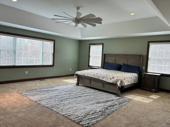 Une chambre à coucher avec un lit, un ventilateur de plafond, une fenêtre et une table de chevet.