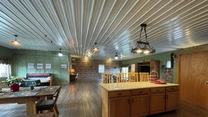 A spacious kitchen with a central island, wooden cabinets, and a high ceiling with linear patterns. - Charming 2-bedroom country home in Middlesex / Potter (Middlesex)