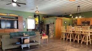 A cozy living room with a flat-screen TV, a fireplace, and a dining area with wooden chairs and a table. - Charming 2-bedroom country home in Middlesex / Potter (Middlesex)