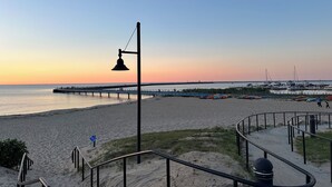 A beach with a pier extending into the water, a walkway, and a trash can. - Charming 2-bedroom cottage steps away from the beach, restaurants, and downtown  (Port Austin)