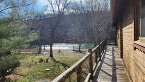Une cabane en bois dotée d’une terrasse offrant une vue sur une rivière et une forêt.