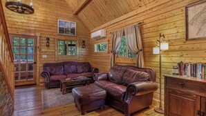 L ’intérieur chaleureux d’un chalet avec des murs en bois, des canapés en cuir, une table basse en bois et une bibliothèque.