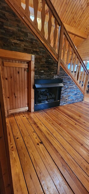 Stairs lead down to a cozy lower level with a fireplace and stone wall.