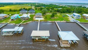 A waterfront property with multiple docked boats, a central pier, and several houses with large windows and balconies. - Coco Cabana (Hackberry)