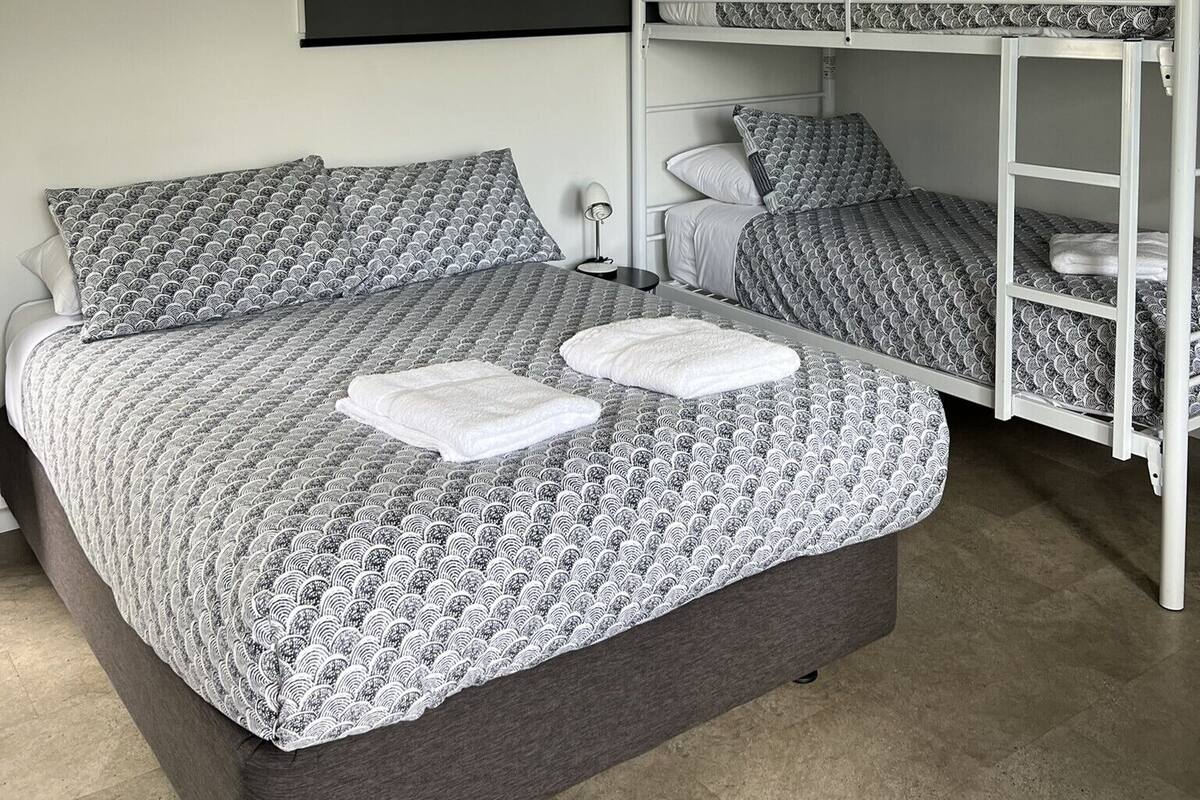 Ein Etagenbett mit gemustertem Bettbezug und Kissen, eine Nachttischlampe und ein weißes Handtuch auf dem Bett.