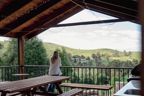 A covered outdoor area with picnic tables and a view of rolling hills. - Buchan Motel  (Buchan)